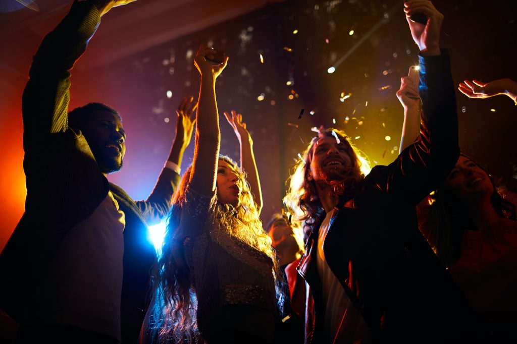 Excited people dancing at concert in nightclub